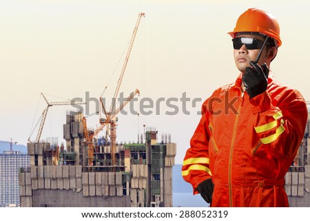 Engineer with radio communication in action control working at high building construction site