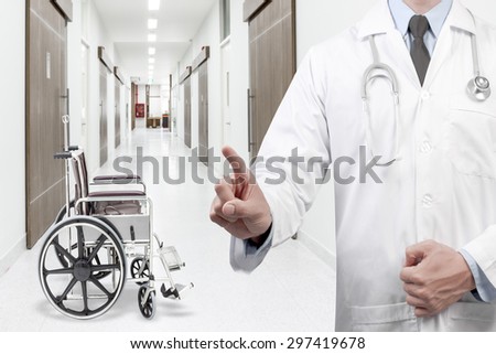 Doctor pointing at empty wheelchair on corridor of hospital