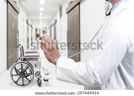 Doctor diagnosis with stethoscope listening heart beat with empty wheelchair on corridor of hospital