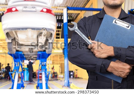 Mechanic holding a clipboard of service order with wrench of service order for maintaining car at the repair shop