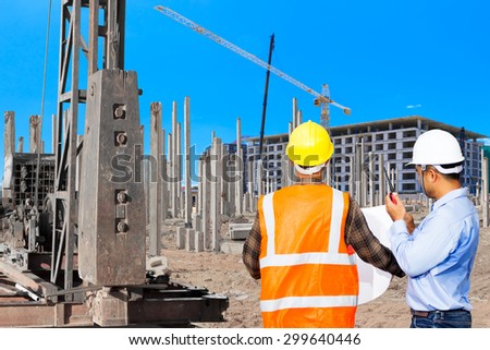 Civil engineer and foreman control working at pile driver works to set precast concrete piles in a construction building area