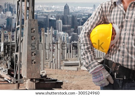 Worker working at pile driver works to set precast concrete piles in a construction site against city metropolitan