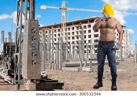Brawny worker at pile driver works to set precast concrete piles in a construction site high building area