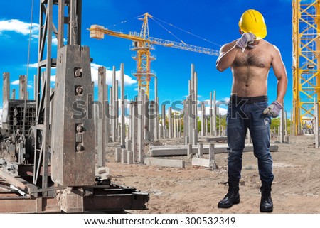 Brawny worker at pile driver works to set precast concrete piles in a construction site