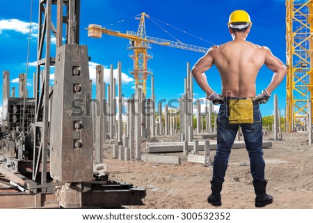 Brawny worker working at pile driver works to set precast concrete piles in a  construction site