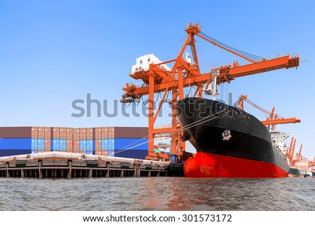 Commercial delivery cargo container and container ship being unloaded in the harbor