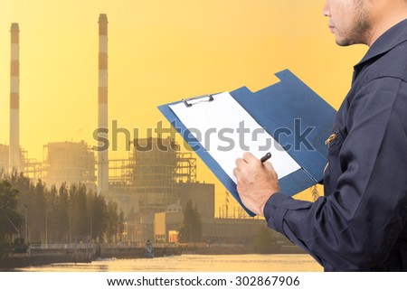 Engineer maintenance recording on clipboard at Industrial power plant in sunset