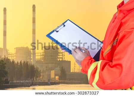 Technician maintenance recording on clipboard at Industrial power plant in sunset