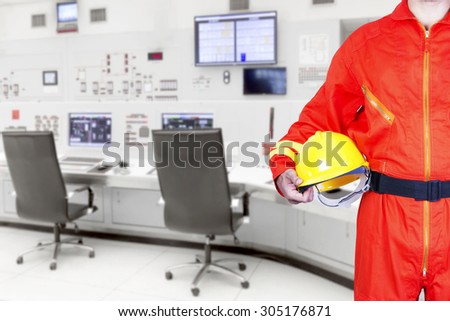 Technician holding hard hat for working at control room of a modern thermal power plant