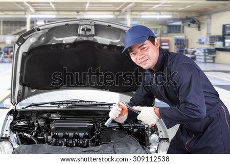 Auto mechanic holding wrench for working in garage repair service