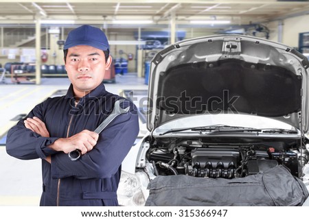 Auto mechanic holding wrench at maintenance repair service station