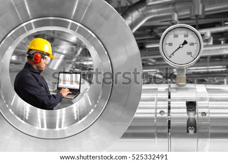 Mechanic using computer for working seen through pipeline gauge pressure equipment at factory industrial