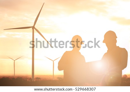 Silhouette of engineer and foreman at wind turbine electricity in sunset