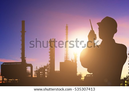 Silhouette of engineer control working by radio communication at petrochemical oil refinery in sunrise