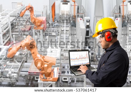 Engineer looking at laptop for programing computer controlling robot hands automation and conveyor belt in the factory