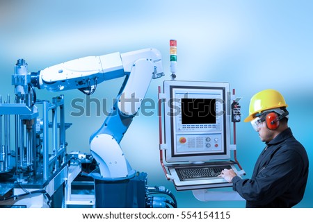 Industry concept and blue tone of engineer use control panel programing automated robot arm in production line of smart factory