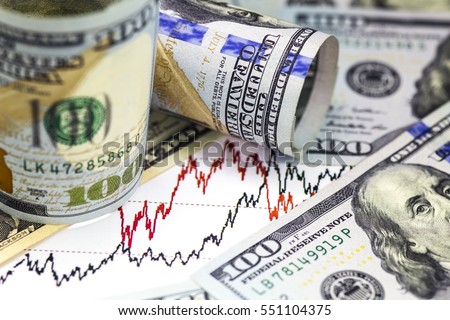 Stock market Charts . Two Hundred rolled us dollar bills  staying on the graph. Two more hundred us dollar bills on the foreground. Macro image. Red and black lines on the chart.