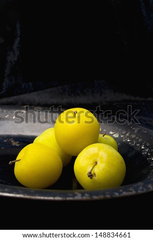 Fresh plums on an old serving dish, black velvet background