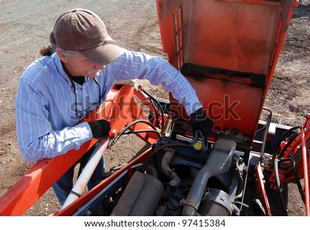 Man removing radiator cap on tractor while conducting an annual tune up, maintenance on the tractor.