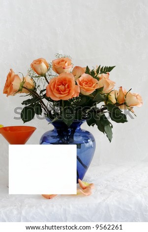 Bouquet of roses and a orange glass with blank text card