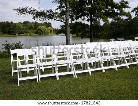 White folding chairs set up in front of lake
