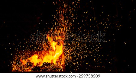 Small BBQ on fire with burning charcoal and flying sparks