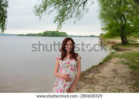 portrait of beautiful pregnant woman near the river on the beach.Beauty Model Girl . Perfect Creative Hair Style. Hairstyle. Future Mother