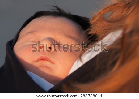 Newborn baby is sleeping on mothers hands in sling
