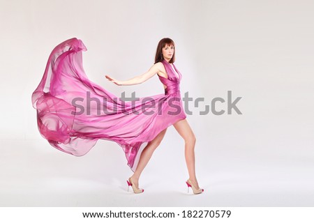 Young beautiful brunette woman in gorgeous fluttering pink dress, motion shot