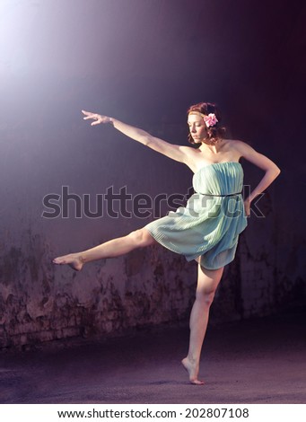 Beautiful happy girl dancing on dark grange background, toned