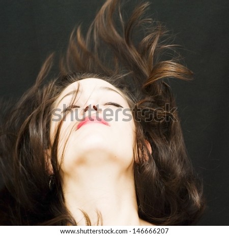 Portrait of a young  woman with  her hair in the wind over black background