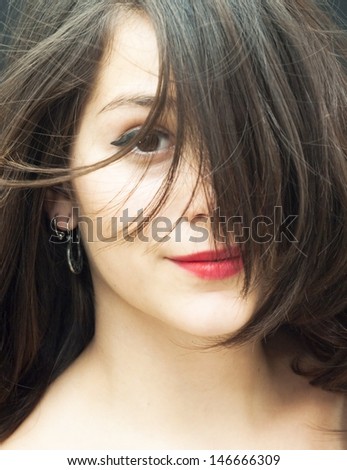 Portrait of a young  woman with her hair in the wind over black background