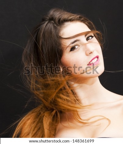 Portrait of an attractive woman and her hair in the wind on black background