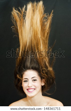 Portrait of an attractive woman and her hair in the wind on black background
