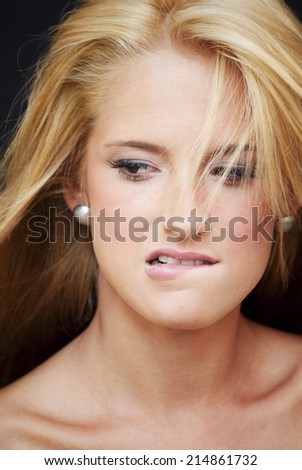 Portrait of Beautiful Blonde Woman biting his lip Over Black Background