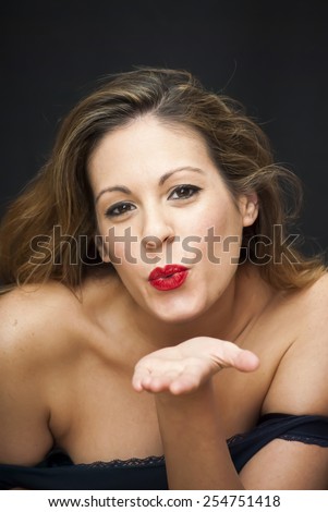Portrait of Beautiful Young Woman giving an air kiss Over Black Background