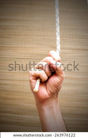 Hand gripping strongly to a rope under tension