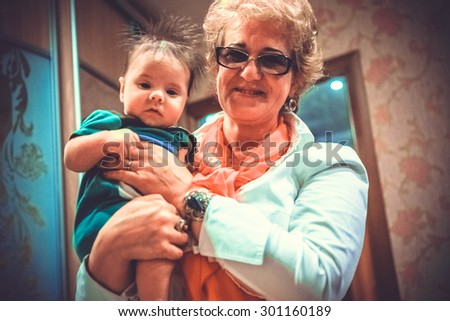 Baby boy in grandma\'s hands. Woman holding the baby and smiles