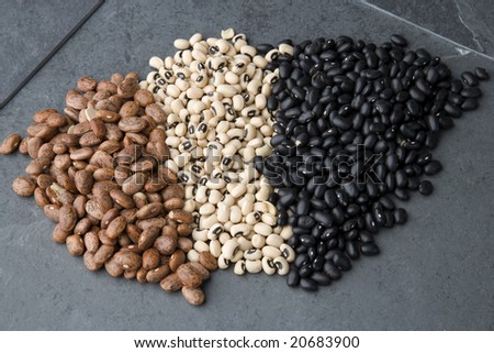 Black, pinto and black-eyed beans on a slate background.