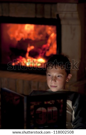 Young boy reading a book in front of the fireplace