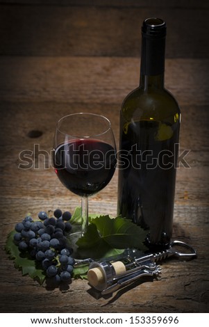 autumnal still life, grapes, cork screw, wine glass and wine bottle on wooden