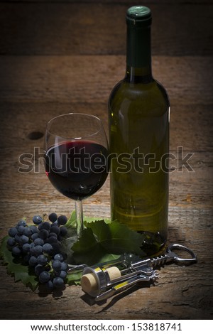 autumnal still life, grapes, cork screw, wine glass and wine bottle on wooden