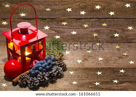 candle lamp, ornaments, grapes and cones on starry old wooden