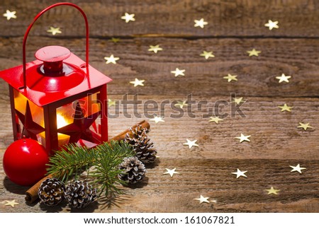 candle lamp, ornament, pine branch, cinnamon and cones on starry old wooden