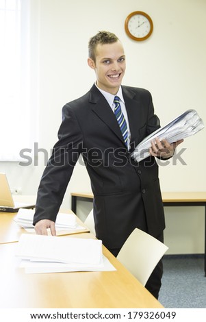 attractive young man in the office with laptop and folder