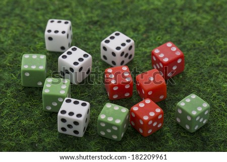 white, green and red dices on green background