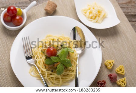 spaghetti with vegetables tomatoes, basil, and heart pasta on plate