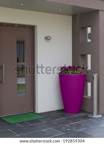door with pink flower pot , bench, and mat
