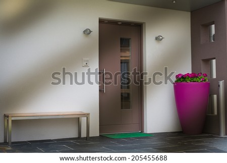 door with pink flower pot , bench, and mat