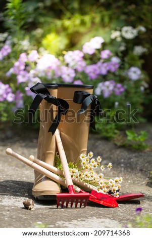garden still life with gum boots, garden tools and flower